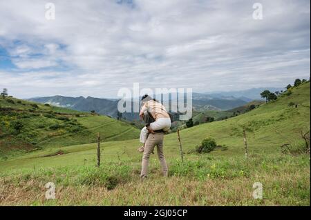 Romantische junge asiatische Paar Huckepack Fahrt auf der Weide Hügel in der Landschaft im Urlaub Stockfoto