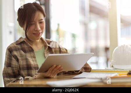 Professionelle weibliche Ingenieurin, die an digitalen Tablette im Ingenieurbüro arbeitet, technische Ausrüstungen, verschwommene Baustelle im Hintergrund Stockfoto