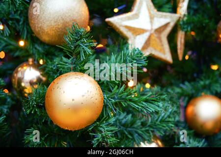 Ornament von goldenen Kugeln und Sternen auf dem Weihnachtsbaum, Nahaufnahme Stockfoto