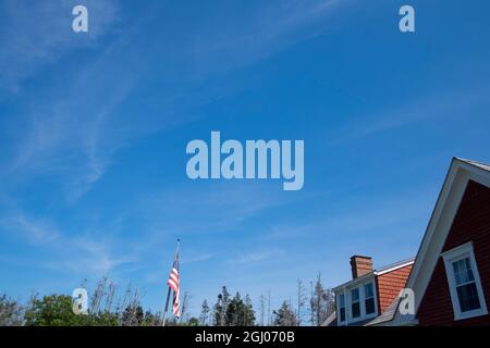 Surreale Ansicht einer amerikanischen Flagge und eines Schindelhauses aus roter Zeder. Auf Monhegan Island in Maine, Neuengland. Stockfoto