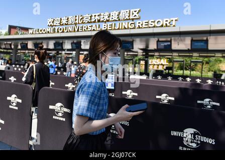 Touristen mit Gesichtsmasken kommen an den chinesischen und englischen Zeichen des universellen Pekinger Resorts vorbei. Universal Beijing Resort ist ein weit verbreitetes Themenpark-Ziel mit mehreren neuen Attraktionen zusammen mit den besten Universal-Fahrgeschäften, Shows und Attraktionen aus der ganzen Welt, die speziell für das kulturelle Erbe Chinas entwickelt wurden. Universal Parks & Resorts, eine Einheit von Comcast NBCUniversal, bietet Gästen auf der ganzen Welt ein immersives Themenerlebnis. Universal's Themenparks sind bekannt für immersive Erlebnisse mit hochspannenden und technolo Stockfoto