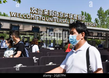 Touristen mit Gesichtsmasken kommen an den chinesischen und englischen Zeichen des universellen Pekinger Resorts vorbei. Universal Beijing Resort ist ein weit verbreitetes Themenpark-Ziel mit mehreren neuen Attraktionen zusammen mit den besten Universal-Fahrgeschäften, Shows und Attraktionen aus der ganzen Welt, die speziell für das kulturelle Erbe Chinas entwickelt wurden. Universal Parks & Resorts, eine Einheit von Comcast NBCUniversal, bietet Gästen auf der ganzen Welt ein immersives Themenerlebnis. Universal's Themenparks sind bekannt für immersive Erlebnisse mit hochspannenden und technolo Stockfoto