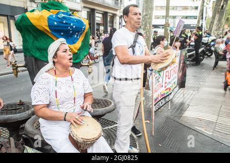 Barcelona, Katalonien, Spanien. September 2021. Demonstranten werden dabei beobachtet, wie sie typische brasilianische Musikinstrumente vor einer brasilianischen Flagge spielen.am Tag der Unabhängigkeit Brasiliens, dem 7. September, hat der Präsident Brasiliens, Jair Bolsonaro, seine Anhänger bei Demonstrationen im ganzen Land zusammengerufen und schürt Bedrohungen für die Demokratie und einen möglichen Staatsstreich. Verschiedene Gruppen und politische Parteien im Land haben dagegen reagiert und Demonstrationen gegen den Präsidenten aufgerufen, in Barcelona hat eine Gruppe von Brasilianern einen Akt gegen den Präsidenten auf den Ramblas (Credit IMA Stockfoto