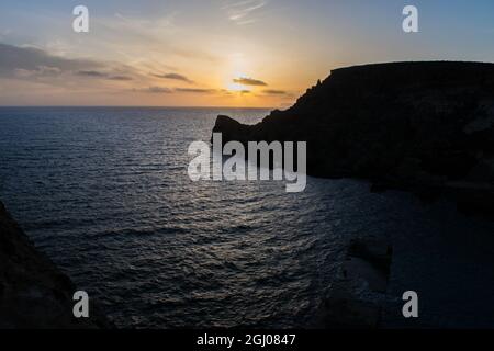 Sonnenuntergang an einem schönen Frühlingstag mit ruhigem Meer, von Anchor Bay, Mellieha, Malta aus gesehen. Stockfoto