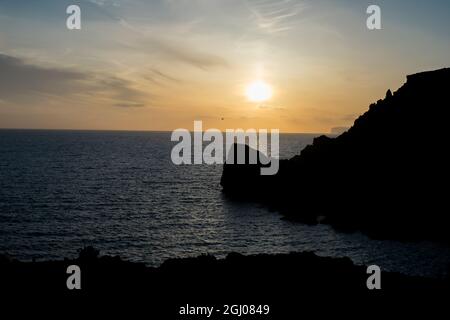 Sonnenuntergang an einem schönen Frühlingstag mit ruhigem Meer, von Anchor Bay, Mellieha, Malta aus gesehen. Stockfoto