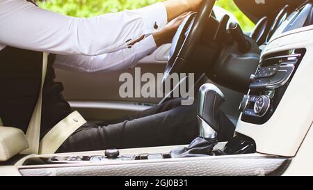 Stilvoller gutaussehender Hindu-Geschäftsmann mit Brille und Bart arbeitet auf dem Rücksitz des Autos und nutzt das Telefon. Sichere und komfortable Luxusreisen Stockfoto