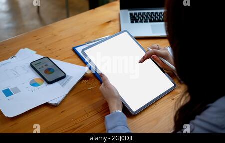 Geschäftsfrau hält einen Stift, um einen leeren weißen Tablet-Bildschirm bei der Arbeit im Büro zu verwenden. Modell. Geschäftsfinanzkonzept Stockfoto