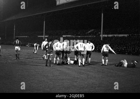 Tottenham Hotspur gegen Manchester United zwei Spieler lagen auf dem Spielfeld in der White Hart Lane, nachdem sie in der dritten Runde des FA Cup erneut aufflammen. Dave Mackay (No.6) zeigt auf Manchester United, innen-rechts Brian Kidd, wobei er seinen Kopf schmerzte, nachdem er sich mit Tottenham rechts hinten Kinnear (am Boden links) zusammengedrückt hatte, was dazu geführt hatte, dass die beiden Männer abgeschickt wurden. Spieler, die den Spurs-Spieler umgeben, sind (von links) Alan Gilzean, George Best, Alan Mullery, Mike England, Pat Jennings, Linker Flügelspieler Beal und Cyril Knowles. Spurs gewann das Spiel 1-0 nach zusätzlicher Zeit. Januar 196 Stockfoto