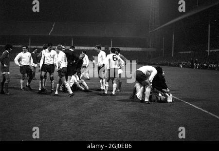 Tottenham Hotspur gegen Manchester United zwei Spieler lagen auf dem Spielfeld in der White Hart Lane, nachdem sie in der dritten Runde des FA Cup erneut aufflammen. Dave Mackay (No.6) zeigt auf Manchester United, innen-rechts Brian Kidd, wobei er seinen Kopf schmerzte, nachdem er sich mit Tottenham rechts hinten Kinnear (am Boden links) zusammengedrückt hatte, was dazu geführt hatte, dass die beiden Männer abgeschickt wurden. Spieler, die den Spurs-Spieler umgeben, sind (von links) Alan Gilzean, George Best, Alan Mullery, Mike England, Pat Jennings, Linker Flügelspieler Beal und Cyril Knowles. Spurs gewann das Spiel 1-0 nach zusätzlicher Zeit. Januar 196 Stockfoto