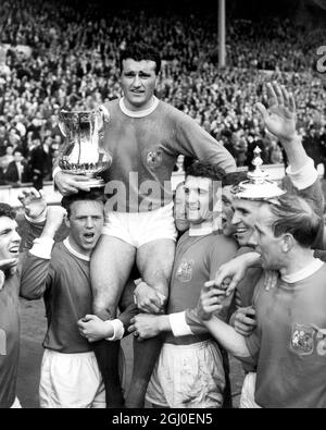 Manchester United captrain Noel Cantwell wird von seinen Teamkollegen geleitet, wobei der FA Cup nach der Präsentation von H.M. der Königin ausgetragen wird. United hatte Leicester City 3-1 besiegt, um den FA Cup zu gewinnen. April 1963. Stockfoto