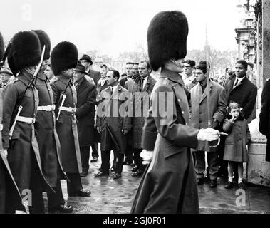 Mitglieder des Benfica Football Teams, die in der zweiten Etappe des Halbfinales der Fußball-Europameisterschaft Tottenham Hotspur spielen werden, beobachten die Wachen vor dem Buckingham Palace, einschließlich Eusebio (ganz rechts). April 1962. Stockfoto