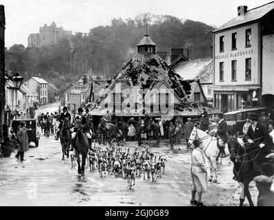 Eine Somerset-Jagd - die West Somerset Foxhounds, die in der High Street von Dunster abfahren - in ihrer Nähe befindet sich der Yarn Market, der vor kurzem restauriert wurde, um als altes Monument zu erhalten. Im Hintergrund ist Dunster Castle. November 1930 Stockfoto