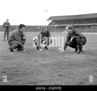 Das West Ham Utd-Team kommt im West Ham Greyhound Stadium zu einer Trainingseinheit auf dem üppigen Rasen, die dem des Wembley Stadions ähneln wird, wo sie Preston North End im Finale am 2. Mai treffen werden. Die hier gezeigten sind von links nach rechts:Roger Byrne, der mittlere nach vorne, Bobby Moore, Kapitän und halber Rücken, und Manager Ron Greenwood. April 1964. Stockfoto