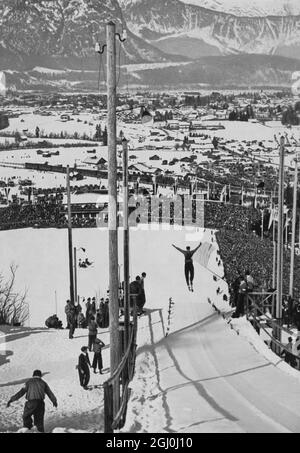 Ein Blick auf den verschneiten Garmisch-Partenkirchen und die sechzigtausend im Skistadion, die einen Sprung in der Kombination Weitsprung beobachten. ©TopFoto Stockfoto