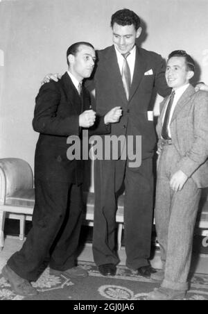 London: Nach dem erleuchteten Fußballspiel zwischen Boxern und Jockeys auf dem Arsenal Ground in London, fanden Jockey Joe Sime, letztjähriger Lincoln-Sieger (links), Boxmeister im Schwergewicht Johnny Williams und Frank Durr (rechts), Jockey des Duke of Norfolk, gemeinsam im Ballsaal des Dorchester Hotels statt, wo ein Festtanz stattfand. 8. April 1952 Stockfoto