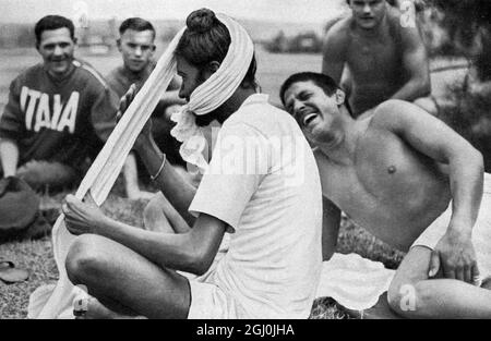 Olympia 1936, Berlin - der italienische Athlet denkt, dass es ein gutes Bild machen würde und lacht, bis er rosa im Gesicht ist. Singh, der Langstreckenläufer, aus Indien bindet seinen Turban vorsichtig an. (Es ist zum Schiessen ...! Denkt der italienischen Athlet, und er lacht sich halbrot, Well Singh, der Langstreckenläufer aus Indien, mit Sorgfalt und Ruhe seinen Turban bindet.) Stockfoto