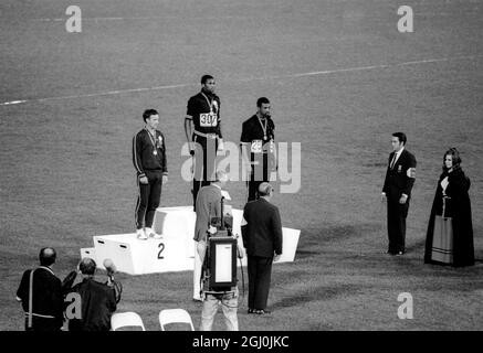 Die Olympischen Spiele 1968, die Gold- und Bronzemedaillengewinnerinnen von Mexiko-Stadt, Tommie Smith (Mitte) und John Carlos (rechts), heben ihre Arme als „schwarze Macht“-Geste während der Zeremonie der Olympischen Spiele. Smith hatte beim 200-Meter-Rennen einen Weltrekord von 19.8 Sekunden aufgestellt. Jeder Mann trug einen schwarzen Handschuh an einer Hand und hob ihn, wobei die Faust geballt wurde, als die US-Flagge angehoben wurde. Perter Norman aus Australien (links) gewann die Silbermedaille. Oktober 1968. Stockfoto