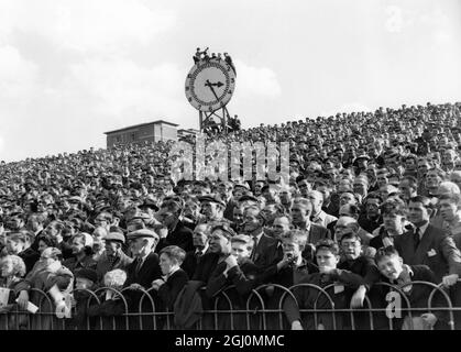 Diese Fußballfans, die jeden Vorfall des Spiels sehen wollten, kletterten auf den Highbury Ground bis zur Uhr und gewannen während des Heimspiels von Arsenal gegen Manchester United am 29. September 1956 einen ununterbrochenen Blick Stockfoto