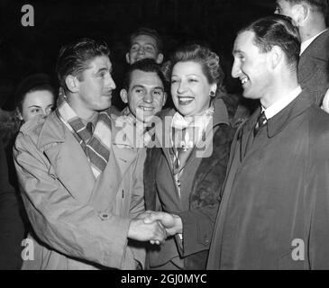 Willkommensort am Bahnhof Victoria London: Jean Baratte, Kapitän der Fußballmannschaft Lille, wird von dem französischen Star Sylvie St Clair und dem Kapitän des Chelsea Football Club, John Harris, begrüßt (rechts). Sie sind von Mitgliedern der beiden Teams umgeben. November 1950 Stockfoto