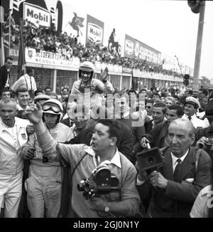 John Surtees und Lorenzo Bandini werden nach dem 35. Grand Prix von Italien, den Surtees in einem Ferrari gewann, von Zuschauern bemunter. Bandini belegte in seinem neuen Ferrari mit 12 Zylindern den dritten Platz hinter dem Neuseeländer Bruce McLaren, der in einem Cooper den zweiten Platz belegte. 8. September 1964. Stockfoto