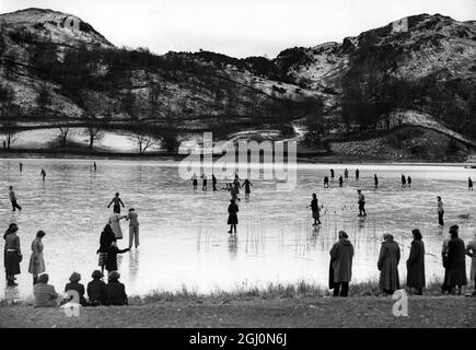 Schnee und harter Frost im Lake District haben perfekte Bedingungen für den Wintersport, das Schlittschuhlaufen auf den Hügeln und das Schlittschuhlaufen auf den Seen geschaffen. Schlittschuhläufer auf dem Eis auf Rydal Water im Lake District, Cumbria, England 29. Januar 1952 Stockfoto