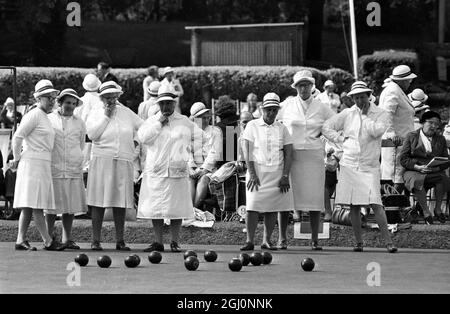 Eine Frau hebt ihren Arm, nachdem ihr Holz den Buben oder weißen Ball getroffen hat, wie andere Mitglieder ihres Teams bei den Amateur National Championships der English Women's Bowling Association im Wimbledon Park, London, England, sehen. 25. August 1969 Stockfoto