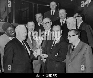 Dr. Luiz Murgel, Delegierter für Brasilien, aktuelle Besitzer der Fußball-Weltmeisterschaft, übergibt die begehrte Jules Rimet-Trophäe an Sir Stanley Rous (links), Präsident der FIFA, nachdem die Welttrophäe heute in London angekommen war. Die Beobachterdelegierten sind von rechts: Dr. Ottorino Barassi (Italien); Jim Maguire (hinten, weißes Haar), aus den USA; Harry Cavan (Mitte, Brille) , Von Nordirland; Lim Zee Siong (hinten) , von Malaya und Dr. Helmet Kaeser (neben Herrn Cavan) , Generalsekretär der FIFA . Das Fußball-Weltcup-Turnier findet im Vereinigten Königreich im Juli 5 Januar 1966 statt Stockfoto