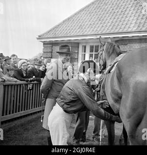 Der australische Jockey George Moore entsetzt Hoffnungsvolles Venture als Trainer Noel Murless sieht lächelnd aus, nachdem Moore und Hopeless Venture am 19. April 1967 bei Newmarket die Wood Ditton Stakes über die Rowley Mile für Dreijährige gewonnen haben. Hopeful Venture gehört der britischen Königin Elizabeth II. Und es war Moores erste Fahrt als Lead Jockey für den königlichen Trainer. 19. April 1967 Stockfoto