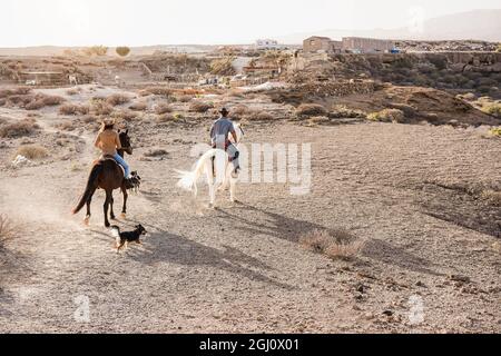 Junges Paar Reiten Pferde tun Ausflug mit Hund Haustiere bei Sonnenuntergang - Schwerpunkt auf Frau zurück Stockfoto