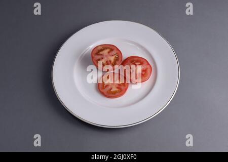 Tomate mit Mozzarella und Basilikum auf einem weißen Porzellanteller Stockfoto