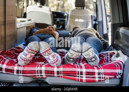 Reife Frauen schlafen im Mini-Van Camper tragen warme Weihnachtssocken - Fokus auf Füße Stockfoto