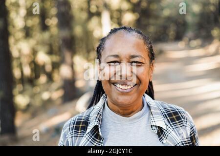 Afrikanische ältere Frau, die im Wald vor der Kamera lächelt - Fokus auf Gesicht Stockfoto