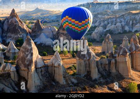 Türkei, Anatolien, Kappadokien, Goreme. Heißluftballon fliegt über/zwischen Felsformationen und Feldlandschaften im Red Valley, Goreme National Park, U Stockfoto