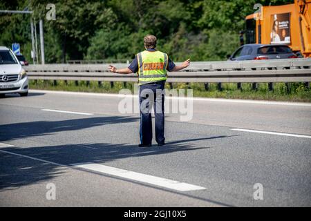 Polizei fährt Autobahn ab. Anlässlich der Eröffnung der Automobilausstellung (IAA) in München wurde am 07.09.2021 die A94 kurz vor der Ausfahrt zum Messegelände die Autobahn A94 mittels einer abseilen-Aktion von Klimaaktivist*innen blockiert. You have receive to Green washing in the Autoindustry. * Polizeibeamter schließt die Straße ab. Am 7. September 2021 wurde die Ausfahrt zur Messe der Autobahn A94 von Klimagerechtigkeitsaktivisten blockiert. Die A94 bringt Autofahrer zur Internationalen Automobilmesse IAA in München. Sie protestieren gegen eine "Greenwashing" der ca. Stockfoto