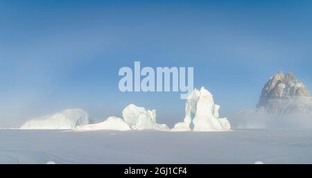 Eisberge erstarrten im Winter im Meereis des Uummannaq Fjord Systems. Hintergrund ist Uummannaq. Grönland, Dänemark. Stockfoto