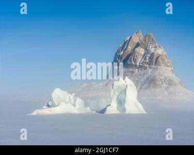 Eisberge erstarrten im Winter im Meereis des Uummannaq Fjord Systems. Hintergrund ist Uummannaq. Grönland, Dänemark. Stockfoto
