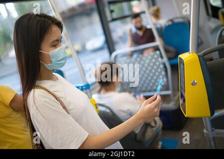 Asiatische Frau, die mit Plastikkarte für die öffentlichen Verkehrsmittel in Bus, Straßenbahn oder U-Bahn-Station ohne Konzetszahlung bezahlt Stockfoto