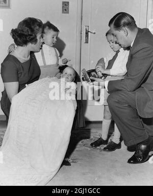 Colin Cowdrey 's drittes Kind eine Tochter Carolyn Susan in Taufroben von Mutter Penny Chiesman gehalten mit Söhnen Jeremy Colin und Christopher Aufnahme der Veranstaltung mit einem Video Dreharbeiten in ihrem Haus in Bickley 1962 Christopher hilft seinem Vater Stockfoto