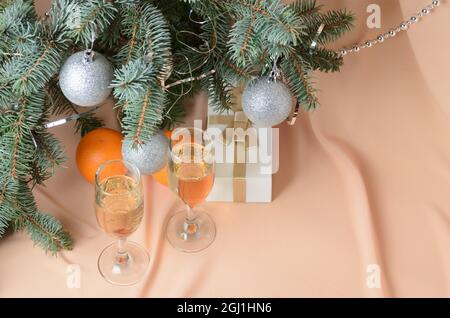 Eine Komposition aus Zweigen eines Weihnachtsbaums, die auf einem Hintergrund mit fleischfarbenen Wellen verziert sind. Selektiver Fokus. Stockfoto