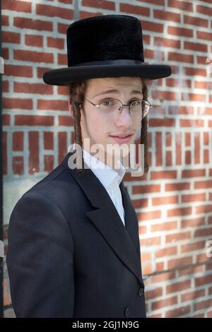 Posierte Porträt eines Jugendlichen chassidischen jüdischen Jungen mit langen lockigen Peyus.. Auf der Lee Avenue in Williamsburg, Brooklyn, New York Stockfoto