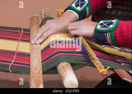 Peru, Chincheros. Peruanische Frau in traditioneller Kleidung in der lokalen Handwerker-Coop-Werkstatt. Stockfoto