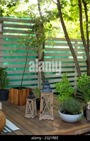 Veranda des Hauses mit hölzernen Laternen dekoriert. Terrasse des Hauses mit Pflanzen in Töpfen im Innenhof. Herbst Hinterhof Haus. Vintage Laternen vor der Haustür Stockfoto