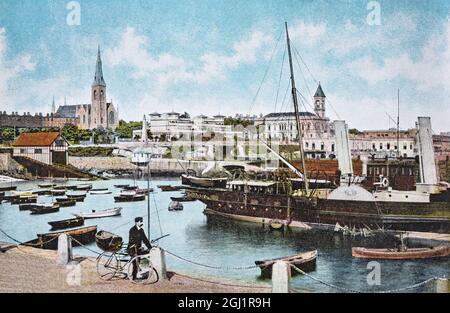 Ein Blick auf den Hafen in Dún Laoghaire, einer vorstädtischen Küstenstadt in der traditionellen Grafschaft Dublin in Irland, aus dem frühen 20. Jahrhundert. Die Stadt wurde nach dem Gesetz von 1816 erbaut, das den Bau eines großen Hafens für Dublin erlaubte. Es wurde als Dún Laoghaire bekannt, bis es zu Ehren des Besuches von König Georg IV. Im Jahr 1821 in Kingstown umbenannt wurde und 1920 seinen heutigen Namen erhielt. Im Laufe der Zeit wurde die Stadt zu einem Wohngebiet, einem Badeort und der Endstation der ersten irischen Eisenbahn. Stockfoto