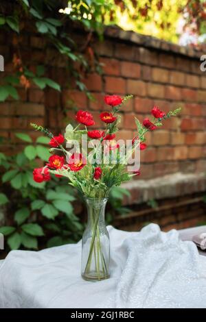 Blumenstrauß aus Mohn in Vase auf Holztisch. Blumenstrauß auf dem Tisch auf der Terrasse Stockfoto