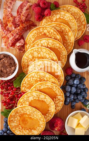 amerikanisches Pfannkuchenbrett mit Speck, Beeren, Ahornsirup, Butter Stockfoto