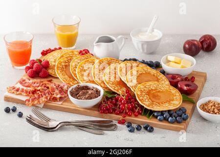 amerikanisches Pfannkuchenbrett mit Speck, Beeren, Ahornsirup, Butter Stockfoto