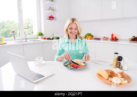 Foto von reifen herrlich schön aussehende lächelnde Frau Oma essen Lachs genießen leckere Mahlzeit Essen im Haus Küche Stockfoto
