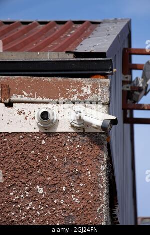 BRAY, IRLAND - 03. Jul 2021: Vertikale Aufnahme von zwei Outdoor-CCTV-Überwachungskameras, die auf einem Industriegebäude in Bray Town, Co. Wicklow, Irland, installiert wurden. Stockfoto