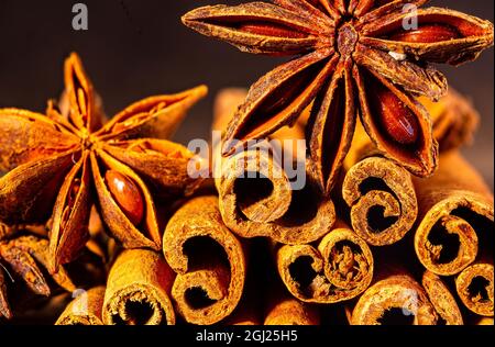 Weihnachtliche Backwürze, Zimtstangen und Anissterne für Weihnachtskuchen, Kekse oder Glühwein auf schwarzem Hintergrund, Makrofoto. Stockfoto