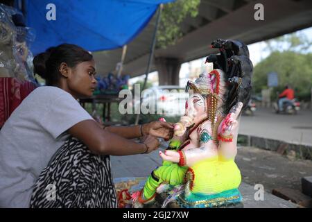 Delhi, Indien - 08-09-2021 -ein Handwerker arbeitet auf einem Fußweg vor dem Ganesha Chaturthi-Fest in Delhi an einem Idol des Herrn Ganesha. Stockfoto